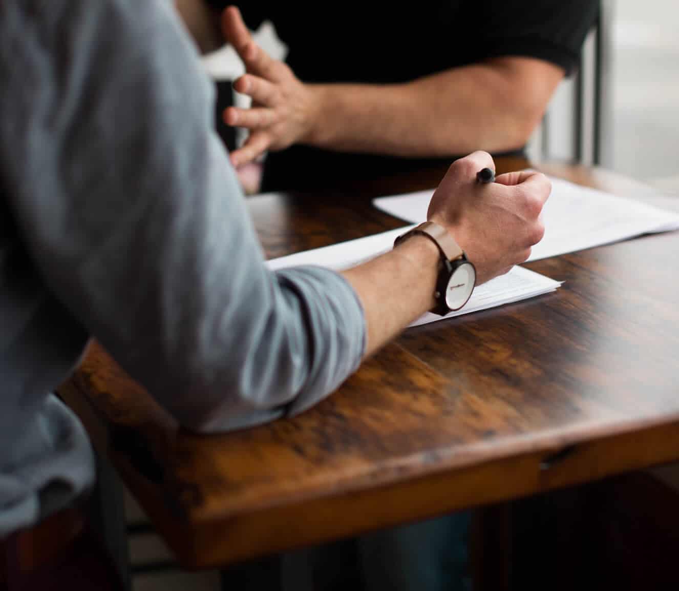 Deux personnes discutent à une table de travail, des documents devant elles